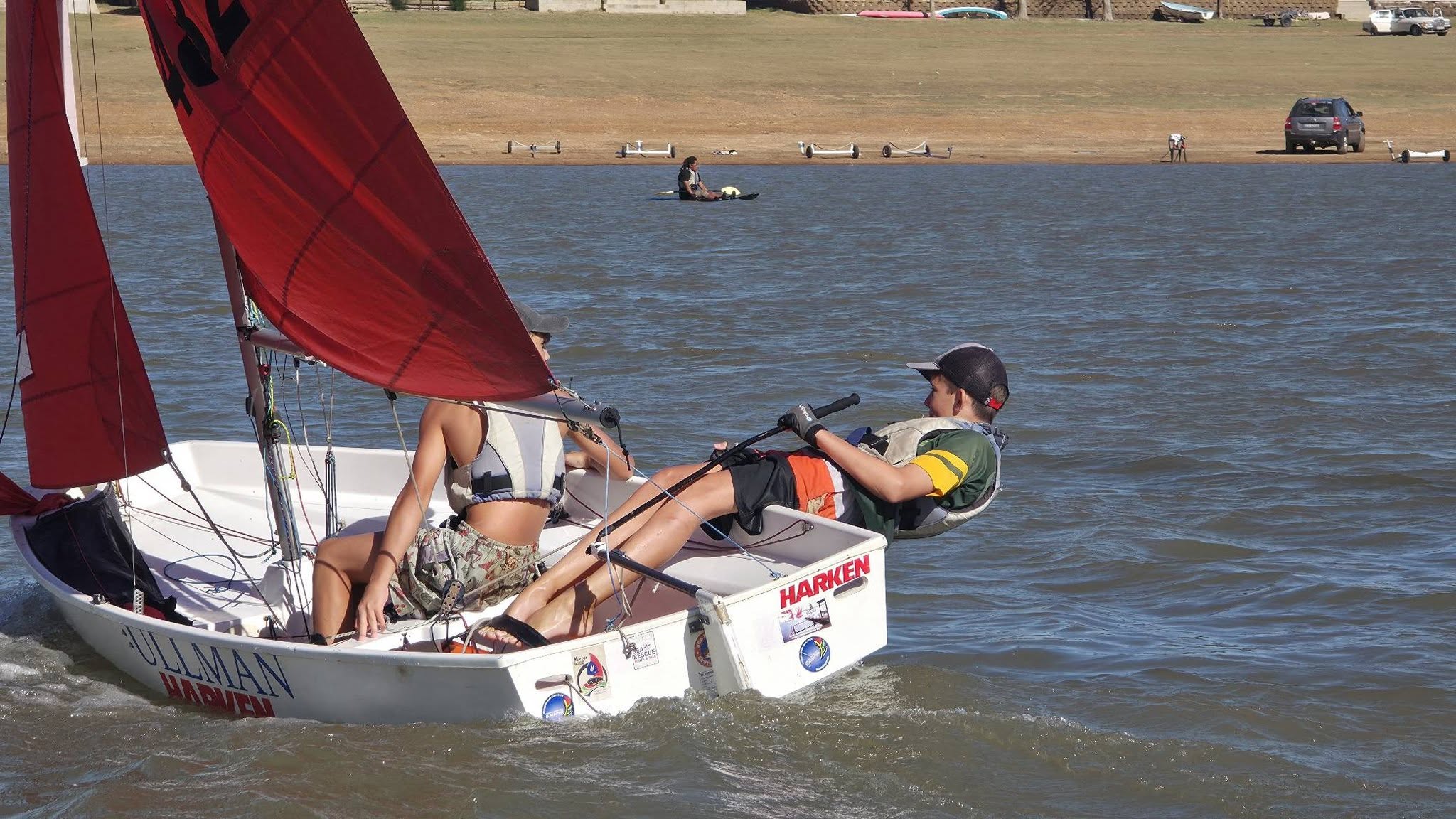 Dinghy sailors flying a red gennaker at Theewater